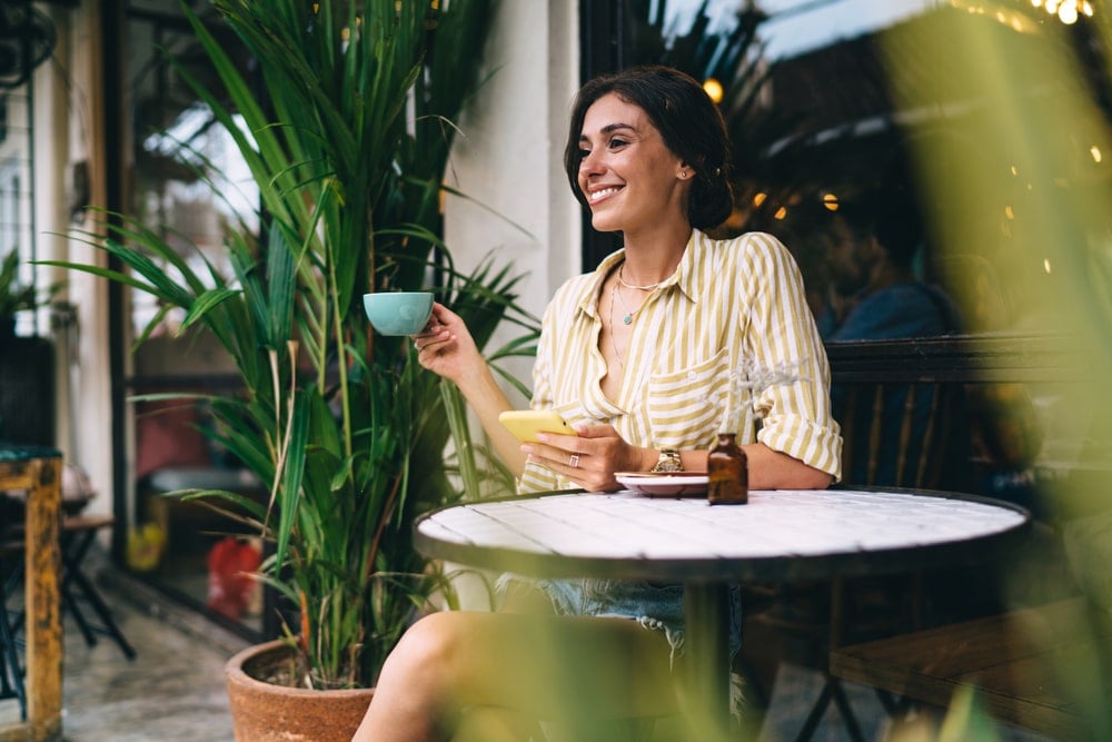 A woman drinking coffee while waiting for her electronic cars being charged