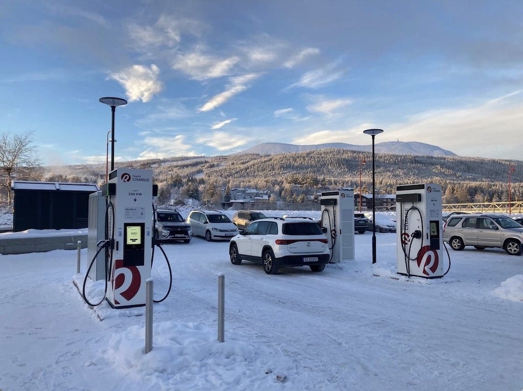 EV cars are being charged at an EV charging point on a sunny day.