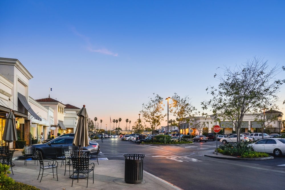 A shopping area with a parking lot at sunset.