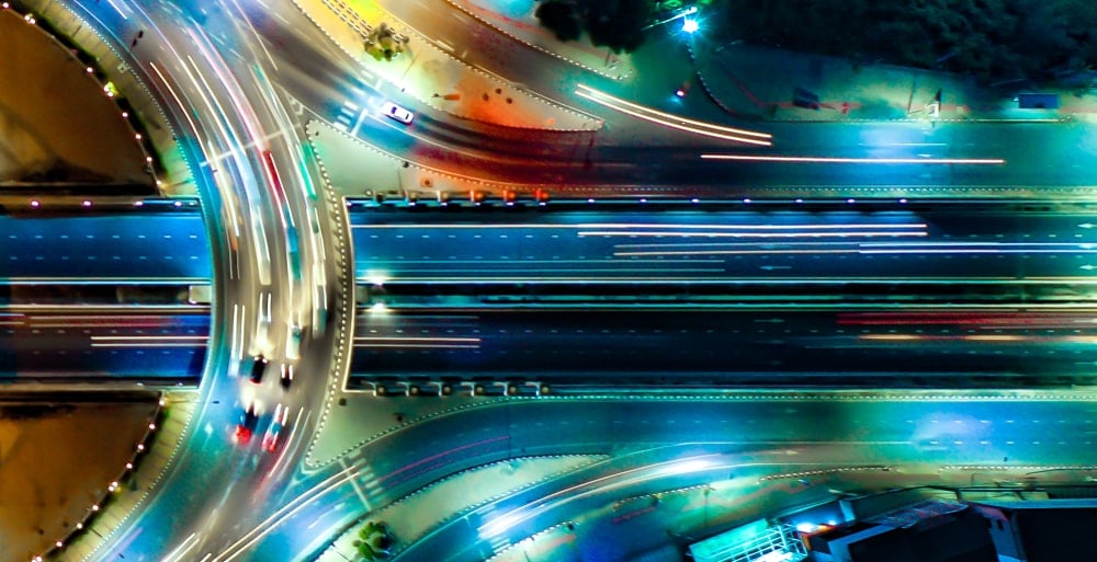 Blick von oben auf einen vielbefahrenen Autobahnverteiler bei Nacht.