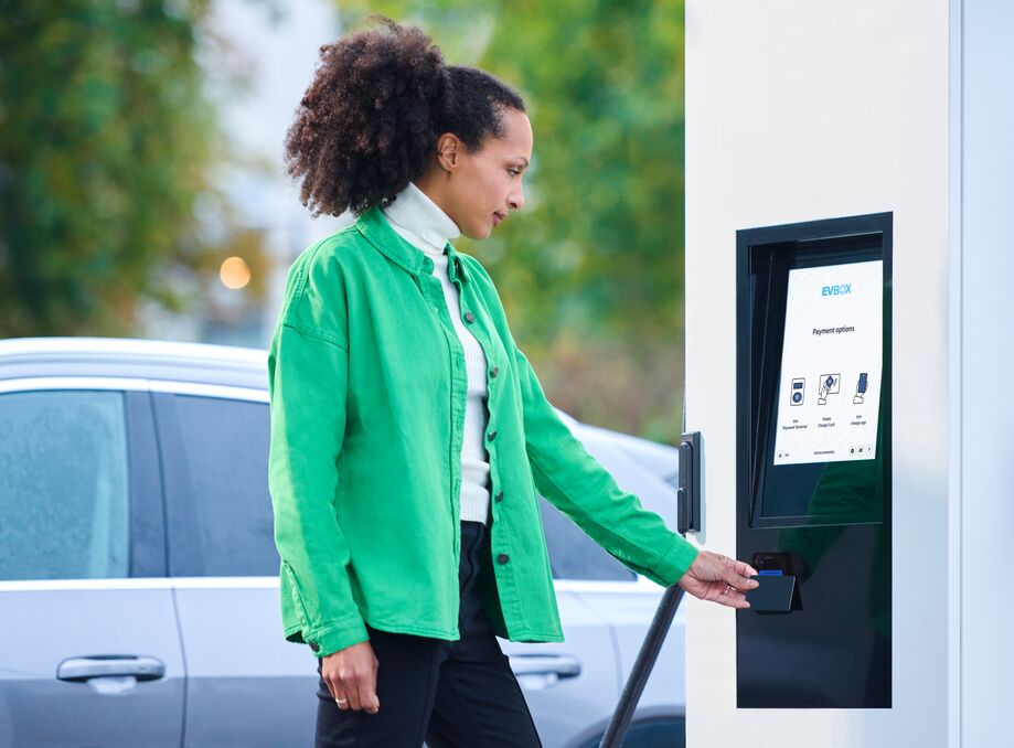 A woman using an EVBox Troniq Modular DC fast-charging station.