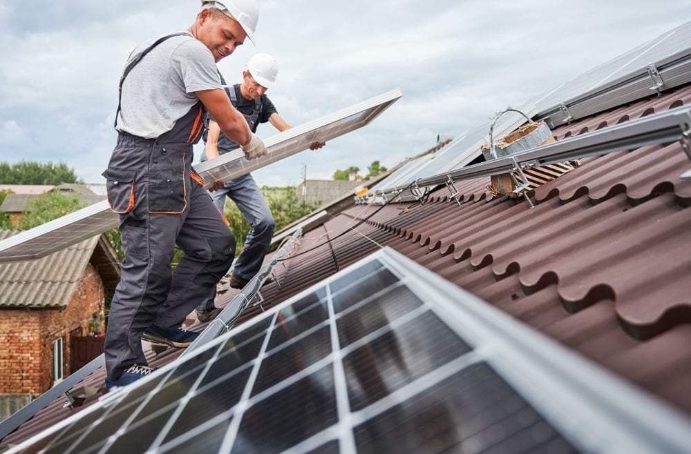 two professionals installing solar panels on a rooftop.