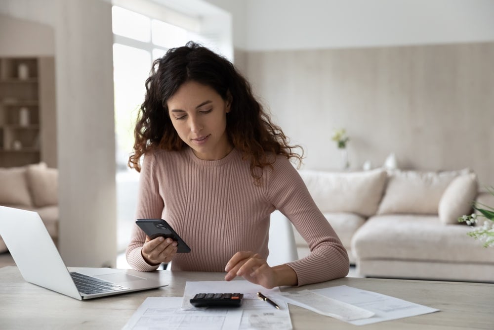 A woman at home calculating the daily energy consumption of her EV.