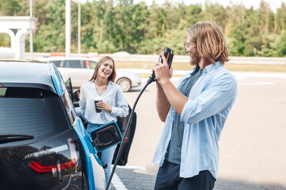 Happy drivers about to charge their car with a DC charging station at their destination.