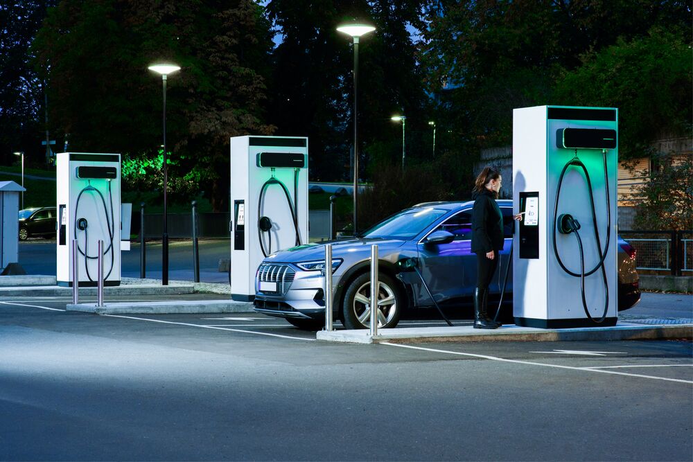 An EV driver at night using a public EVBox Troniq Modular DC charging station