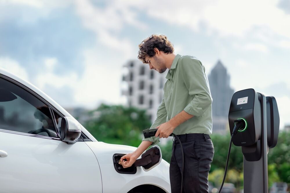 Homme utilisant la borne de recharge publique EVBox Liviqo pour recharger sa voiture.