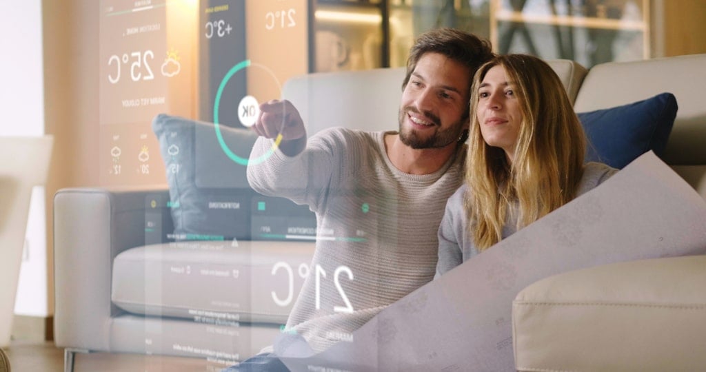 A couple on the couch using a futuristic hologram that represents the use of a energy management system.