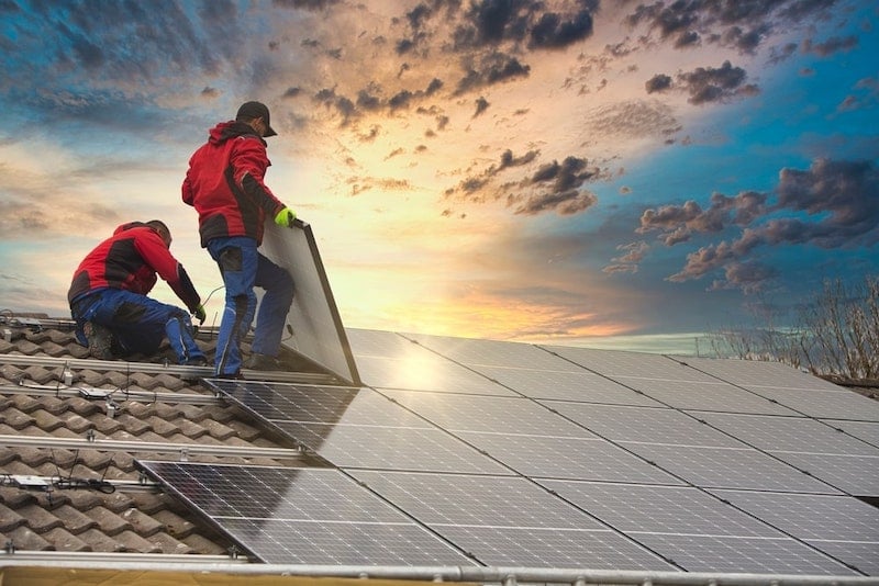 Two experts installing solar panels on the roof.