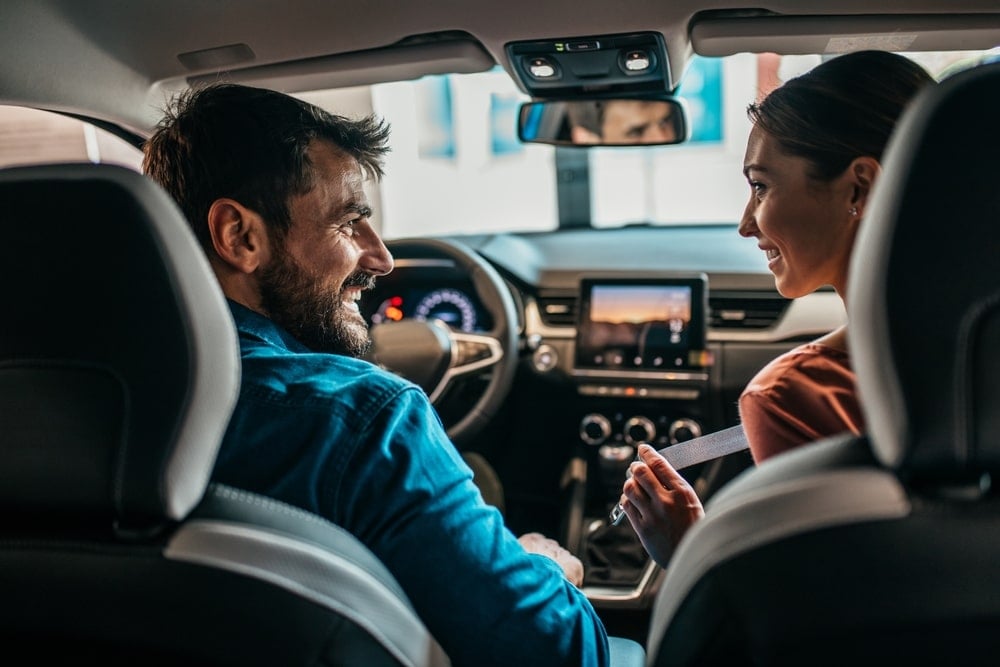 A couple is talking to each other while getting in the car.