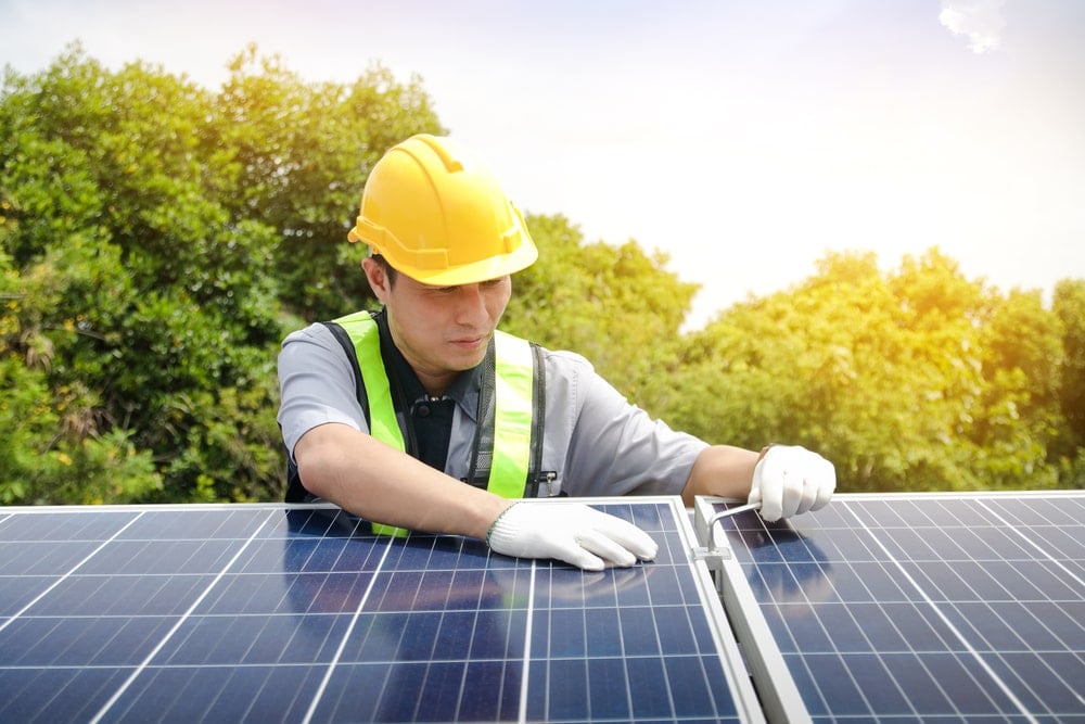 An installer is installing solar panels on a rooftop.