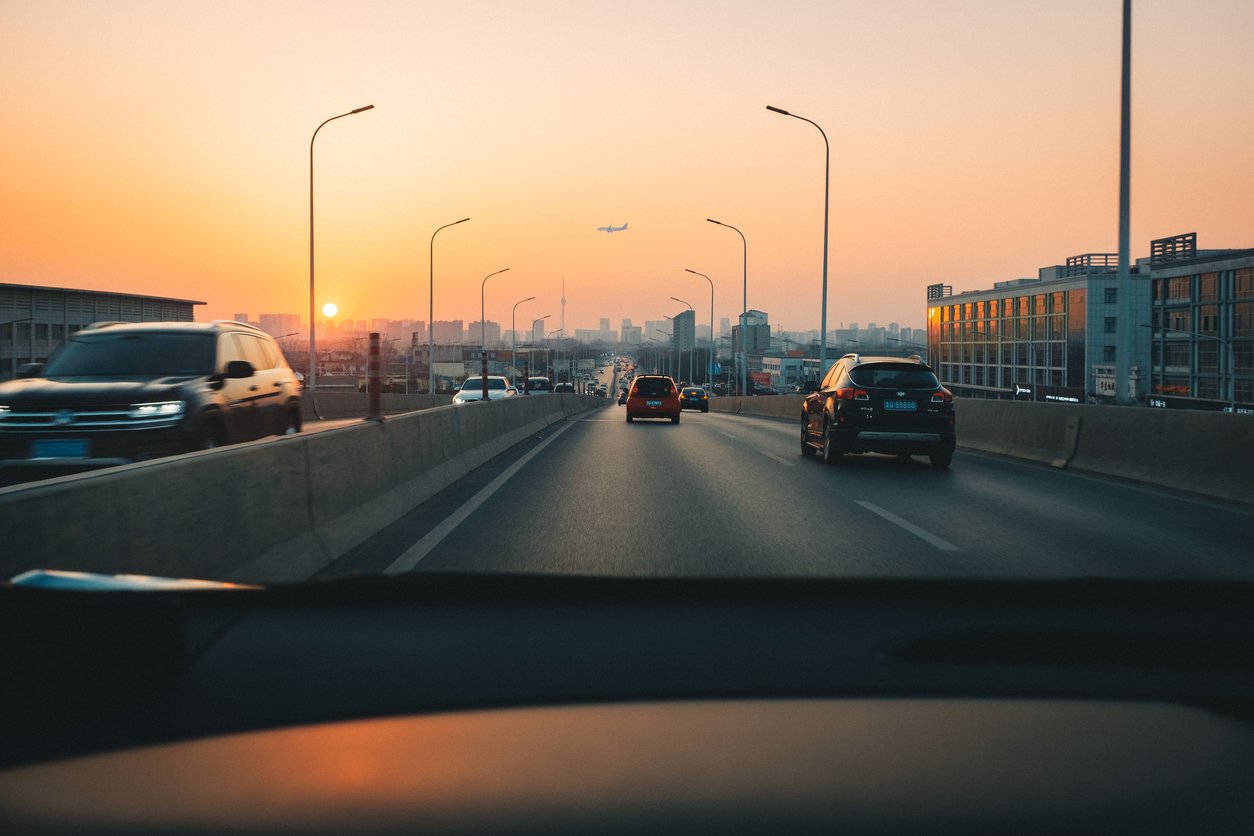 A shot taken from the inside of a vehicle while driving on a highway during sun set.