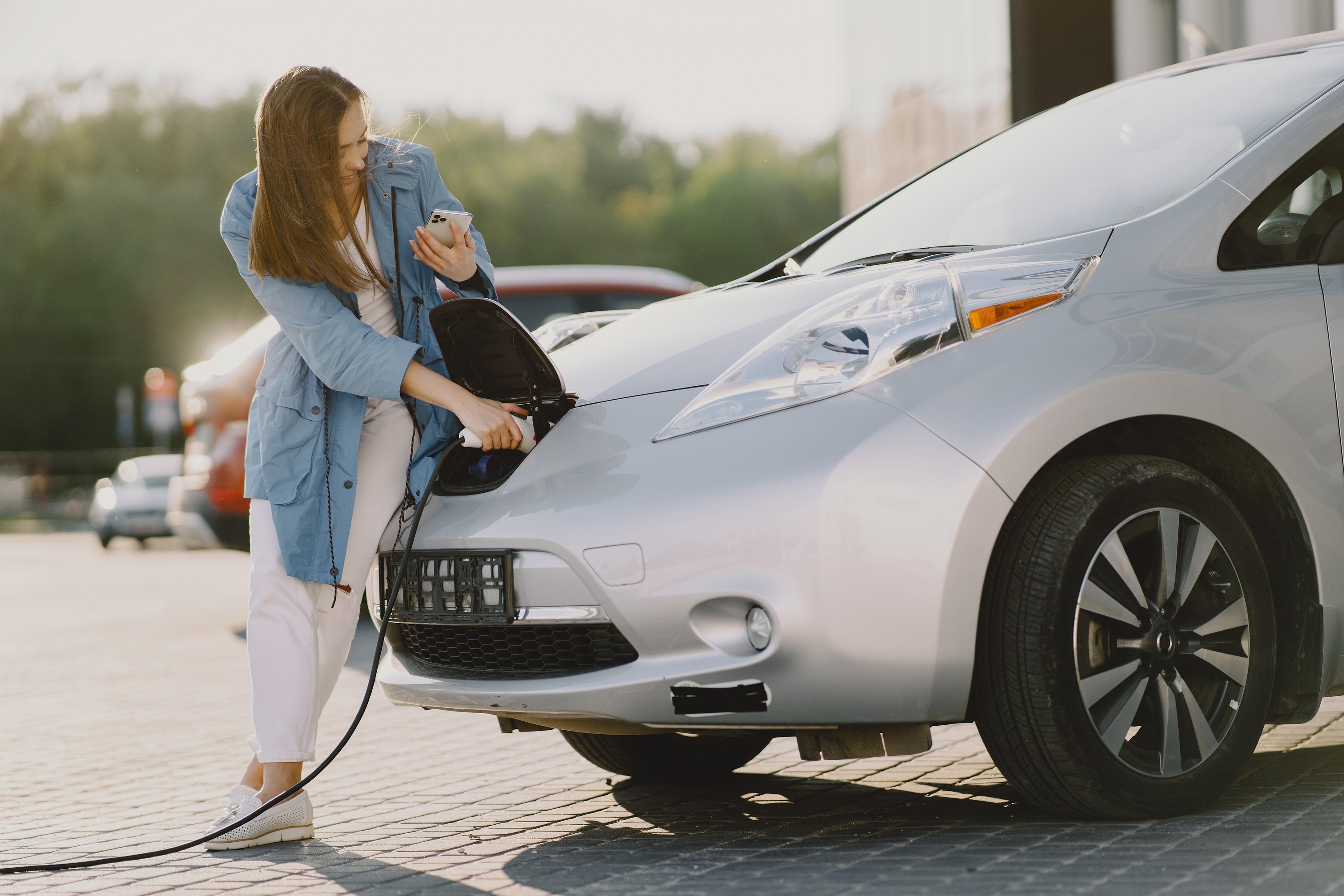 Vrouw lacht en laadt elektrische auto op.