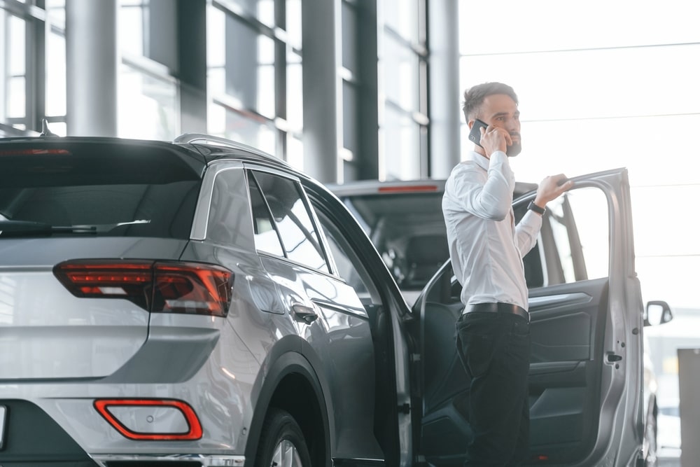 Man talking on cell phone outside his car.