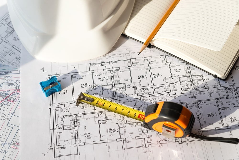 A blueprint of a location with a meassuring tool and a notepad to plan upcoming construction work.