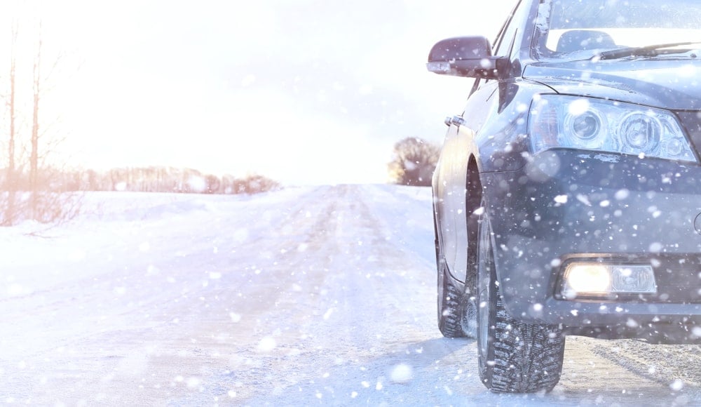 An EV drives on a snowy road in the snow.