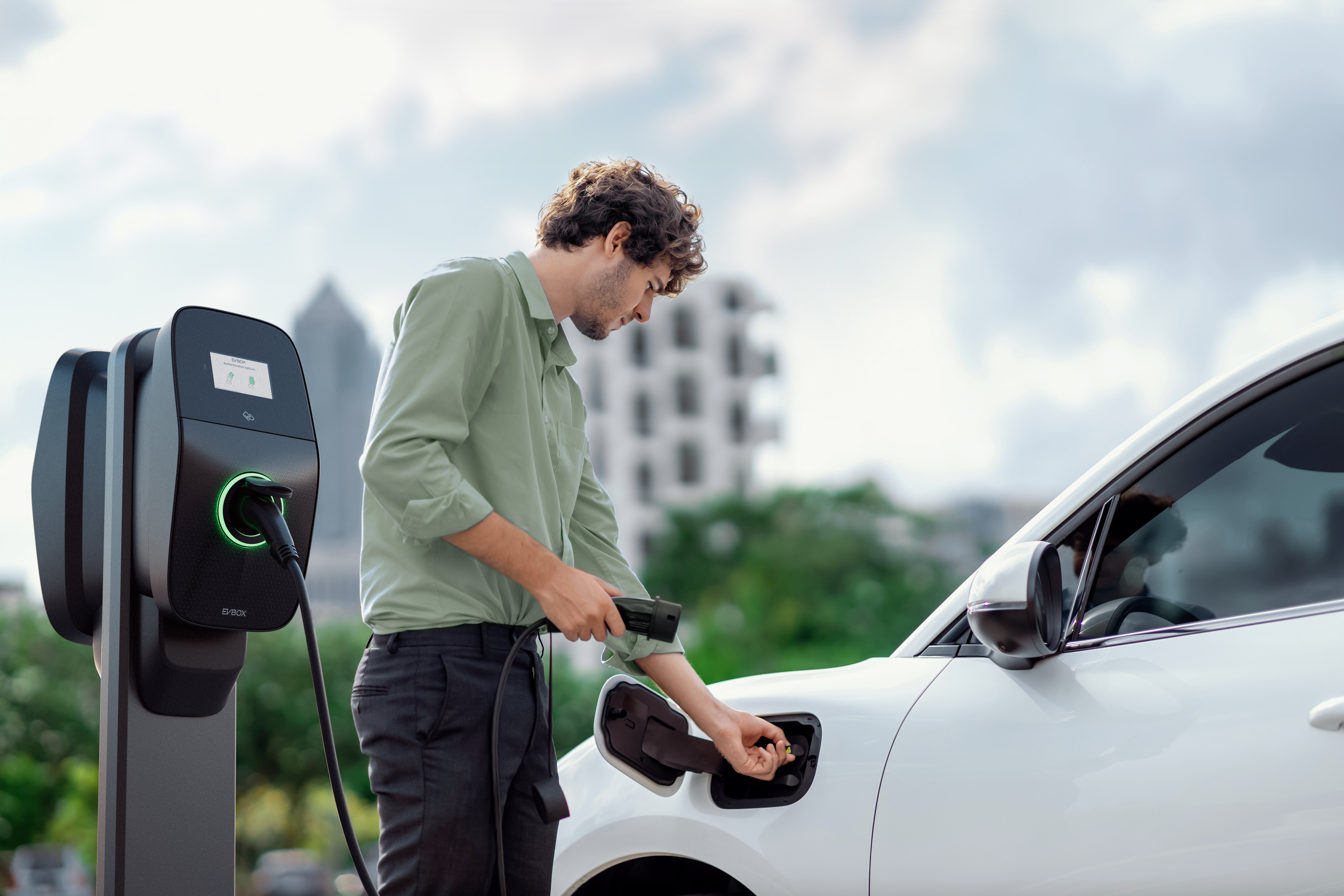 Man using EVBox Liviqo AC business charging station to charge his car at the office.