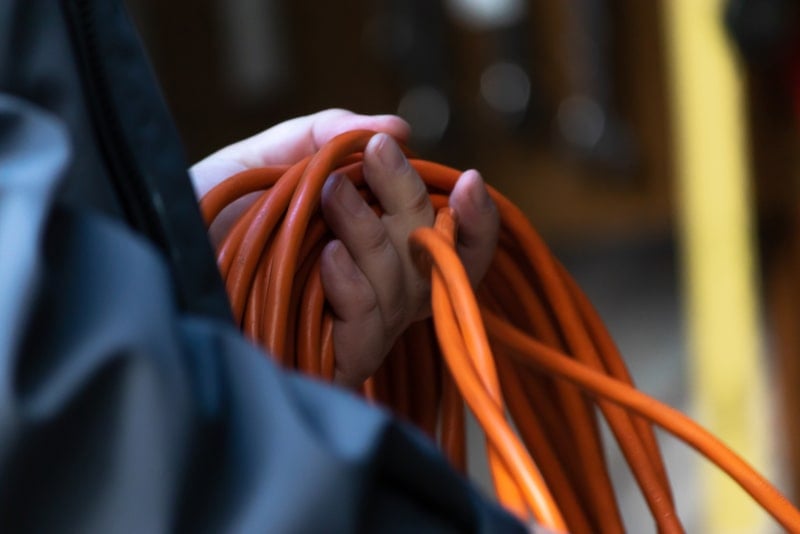 Someone unravelling an extension cord to charge their car in the driveway in an unsafe fashion.