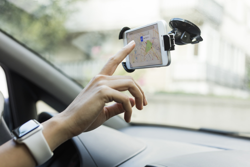 A driver looking for available charging stations on a smartphone.