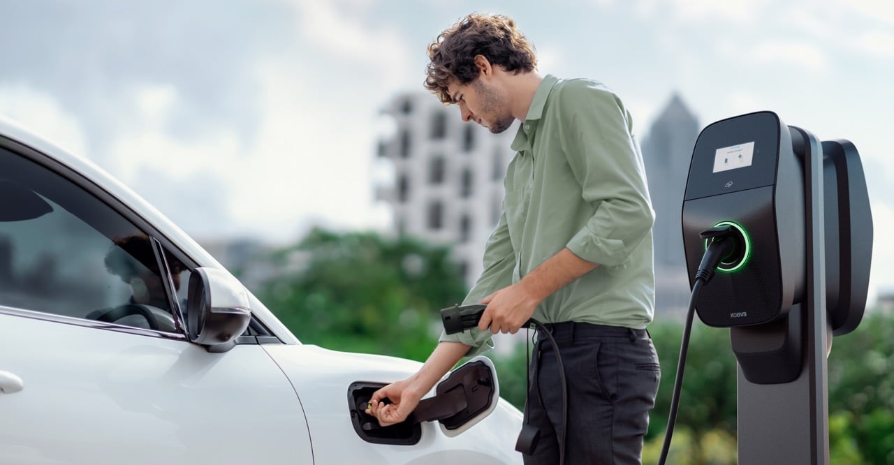 Man using EVBox Liviqo AC charging station to charge his car at the office.