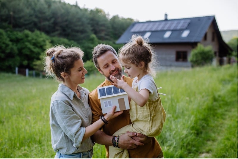 A mother and father explaining the concept of solar panels to their daughter in their garden.