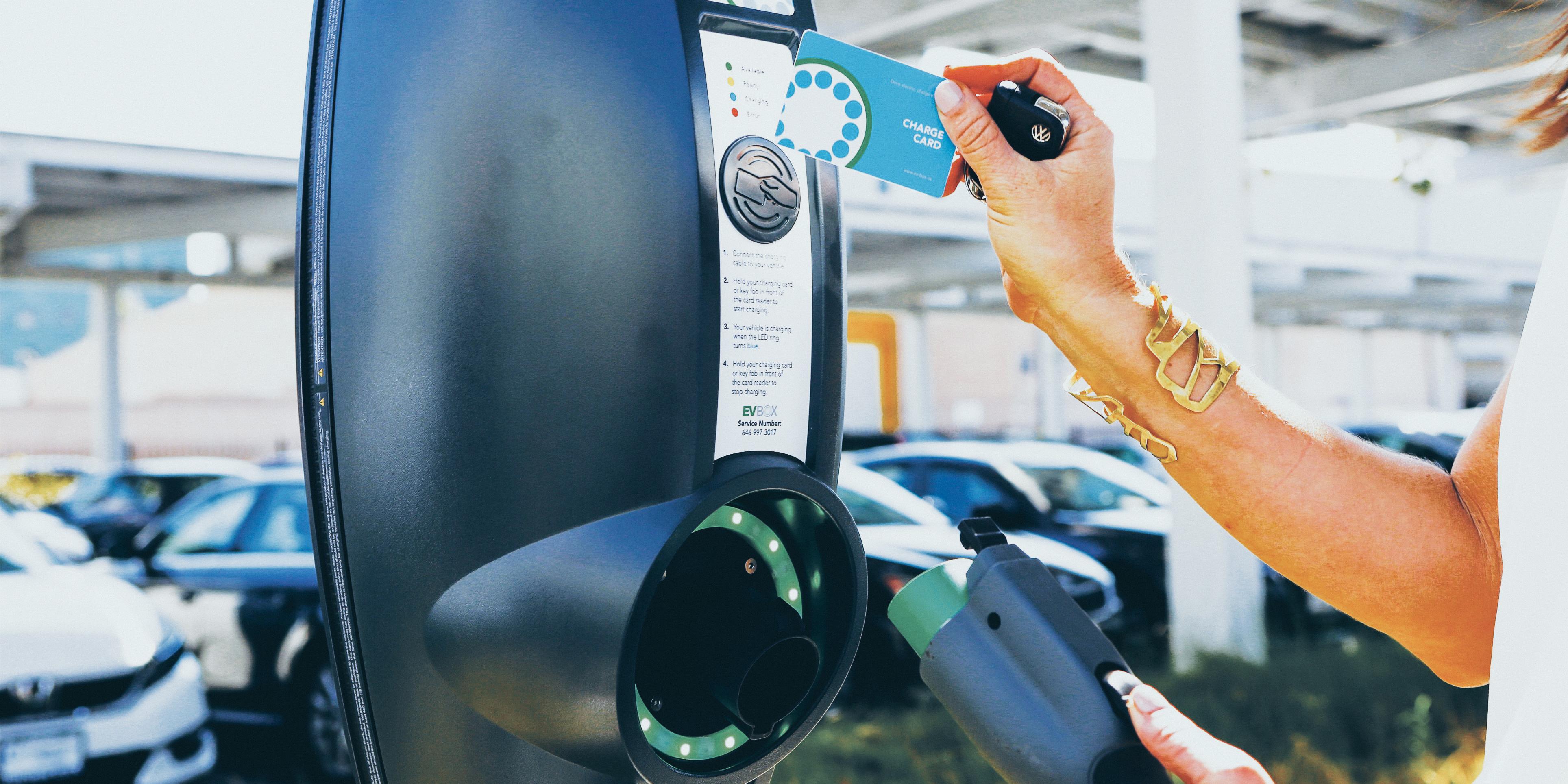 Woman using charging card to pay at an EVBox BusinessLine charging station.